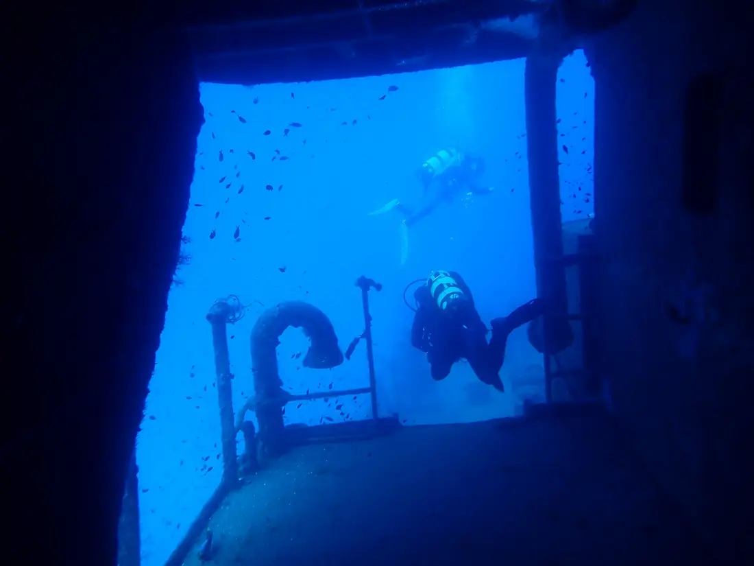 Duiker tijdens een wrakduik in het indrukwekkende binnenste van het Um El Faroud schip bij Malta